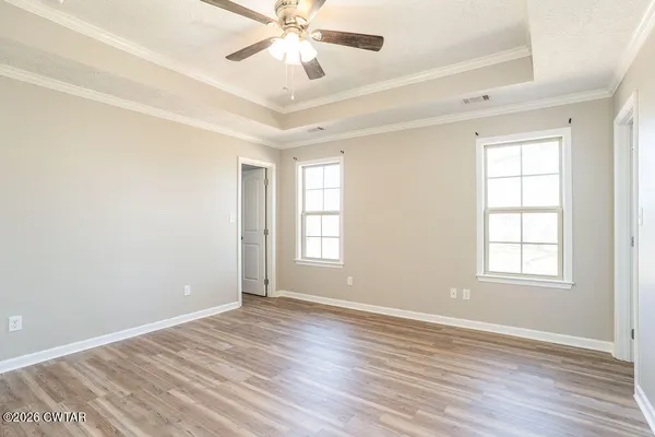 an empty room with wooden floor fan and windows