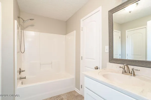 a bathroom with a bathtub shower sink and a mirror
