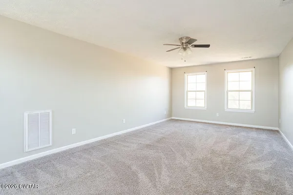 an empty room with windows and ceiling fan view