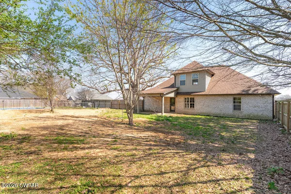 a brick house next to a yard with a large tree