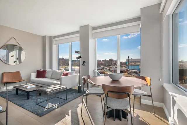 a dining room with couches a large mirror and a dining table with the kitchen view