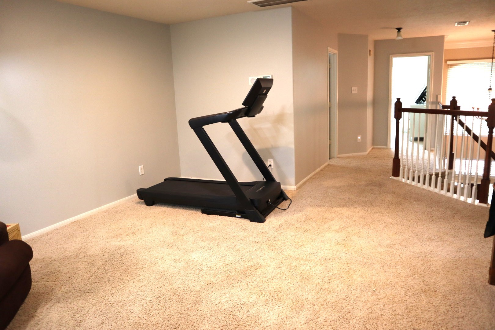 19114 Emory Trail Spring, TX 77388 - Photo 21 of 32 The Game Room features neutral-toned carpet and walls. There's a railing along the hallway, and natural light filters in through windows, creating a bright and inviting atmosphere.
