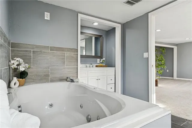 a bathroom with a tub sink and mirror