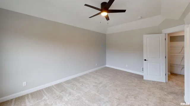 an empty room with a ceiling fan and carpet