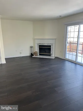 an empty room with wooden floor fireplace and windows
