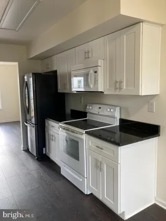 a kitchen with granite countertop white cabinets and stainless steel appliances