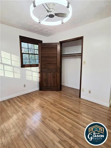 a view of an empty room with a window and wooden floor