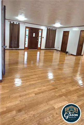 a view of an empty room with kitchen and a window