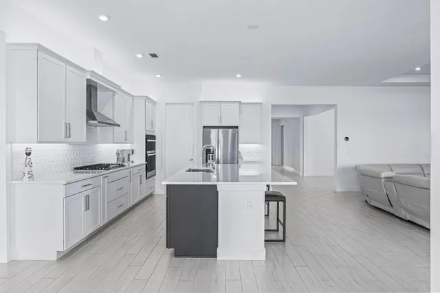 a kitchen with stainless steel appliances kitchen island granite countertop a stove a sink and a refrigerator