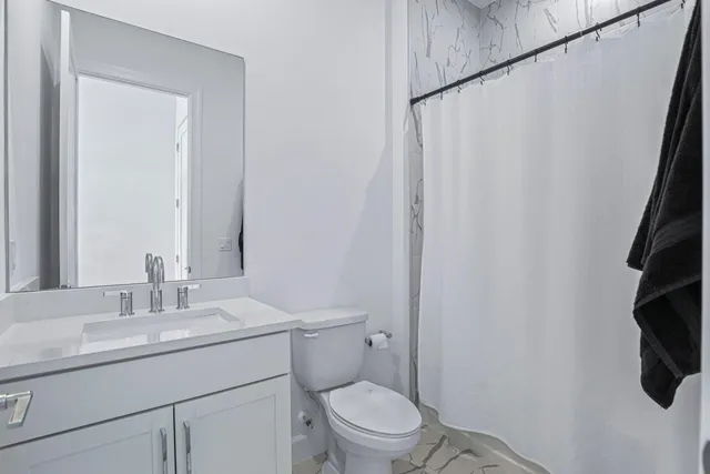 a bathroom with a granite countertop sink toilet and a mirror