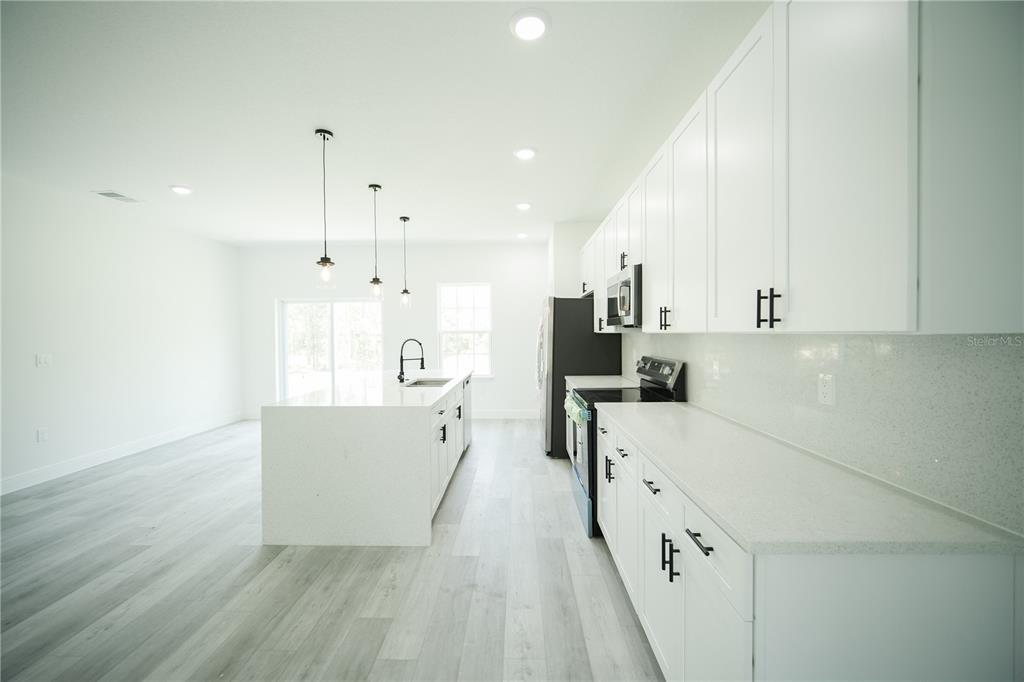 13265 Southwest 85th Circle Ocala, FL 34473 - Photo 47 of 53 a large white kitchen with wooden floor and a sink