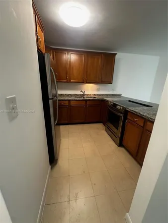 a kitchen with granite countertop a refrigerator a sink a stove a microwave a sink and a counter top