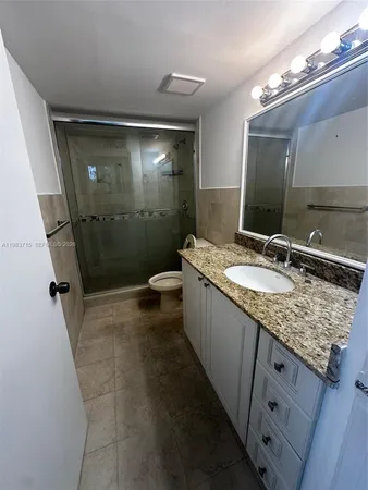a bathroom with a granite countertop sink toilet and shower