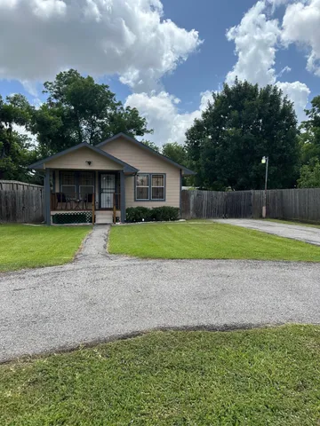 a view of a house with a yard and large trees