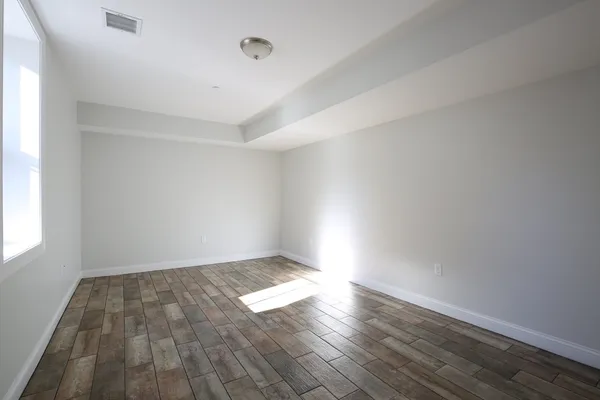 an empty room with wooden floor and windows