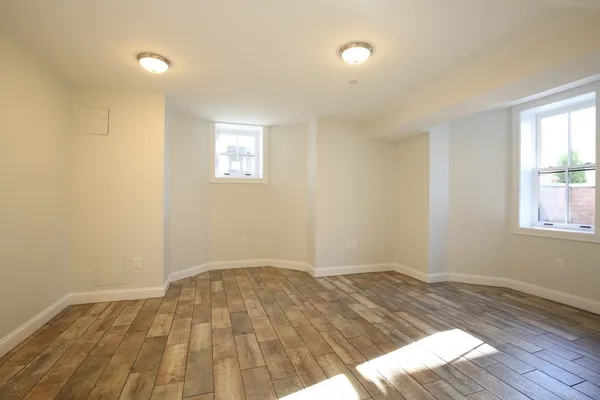 an empty room with wooden floor and windows