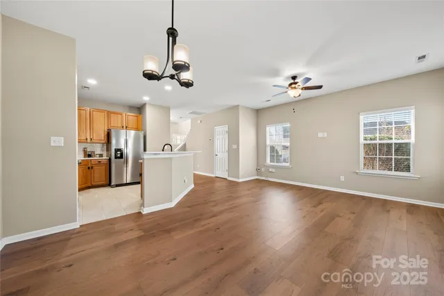 a view of an empty room with kitchen and window