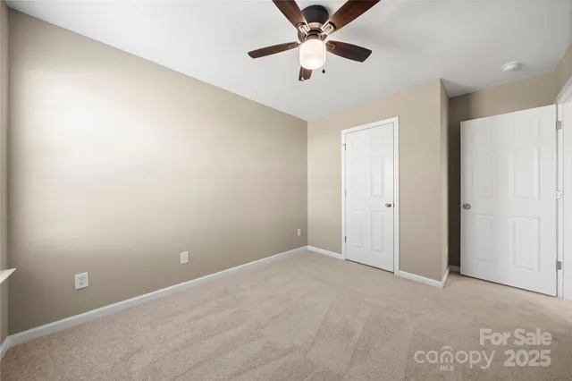 an empty room with a ceiling fan and carpet