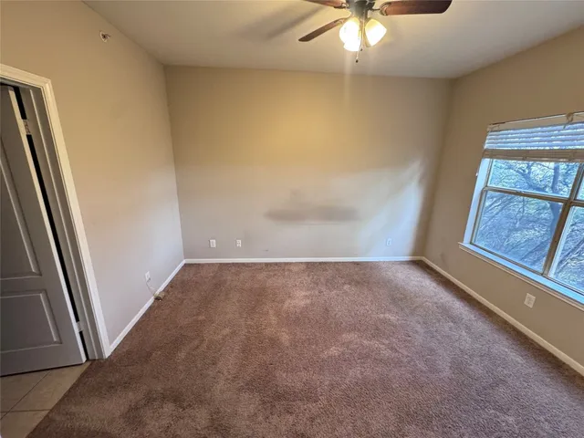 an empty room with a chandelier fan and window
