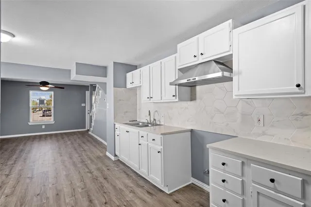 a kitchen with granite countertop a sink cabinets and wooden floor