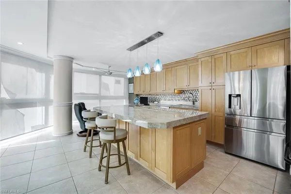 a kitchen with a refrigerator a microwave oven a sink and a dining table with chairs