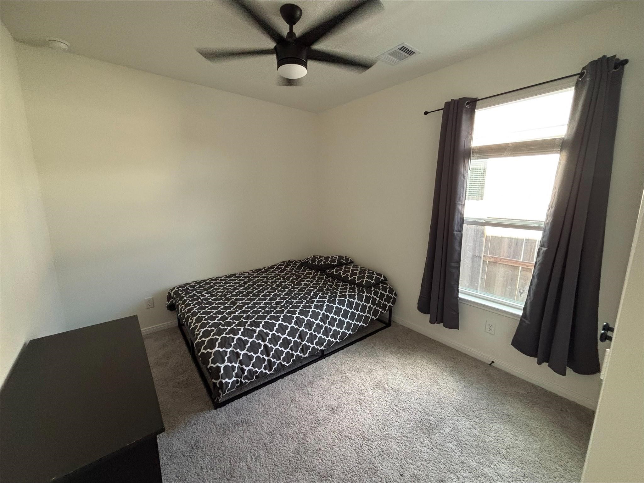 1323 Rosemead Drive Rosharon, TX 77583 - Photo 18 of 27 Cozy third bedroom with abundant natural light, plush carpeting, and a modern ceiling fan for comfort.