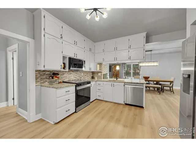 a kitchen with granite countertop a stove a sink dishwasher and a refrigerator with wooden floor
