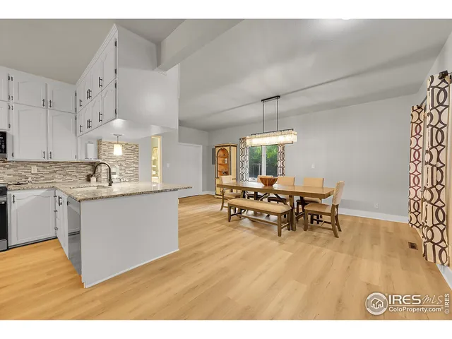 a kitchen with stainless steel appliances kitchen island granite countertop a sink dishwasher a stove a dining table and chairs with wooden floor