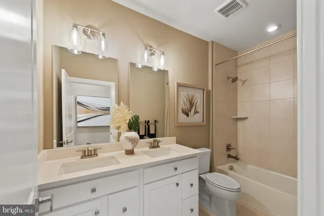 a bathroom with a bathtub shower sink vanity mirror and toilet