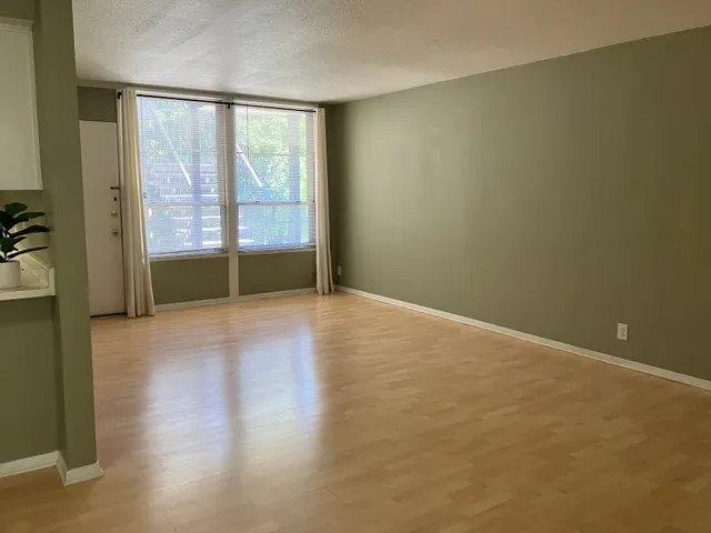 a view of an empty room with wooden floor and a window