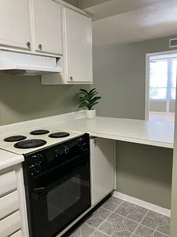 a kitchen with granite countertop a stove and a white cabinets