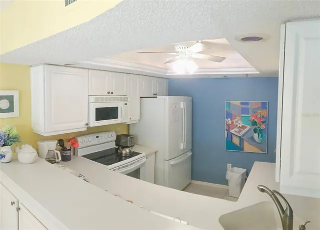a kitchen with stainless steel appliances a refrigerator a sink a stove and white cabinets