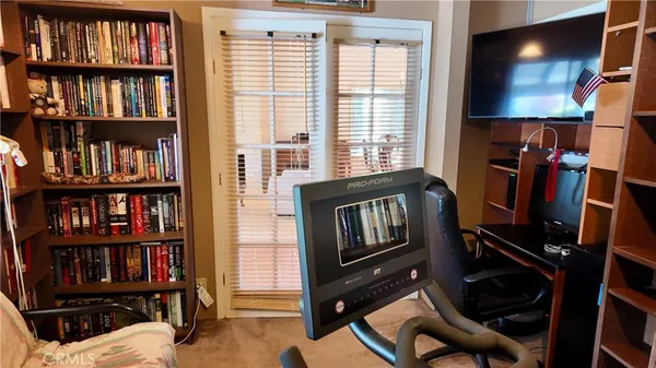 a view of a workspace with bookshelf and a window