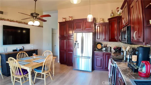 a kitchen with stainless steel appliances granite countertop a stove top oven a refrigerator a dining table and chairs with wooden floor