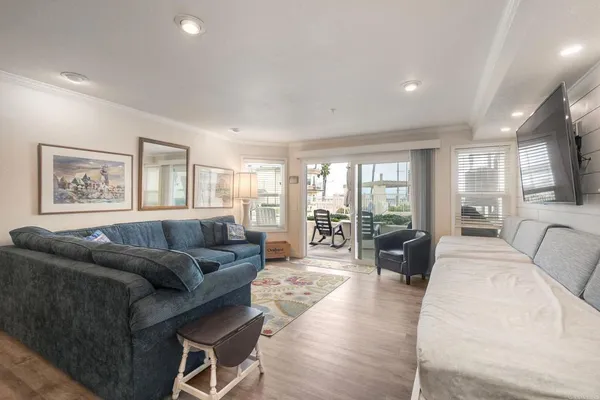 a living room with furniture large windows and wooden floor