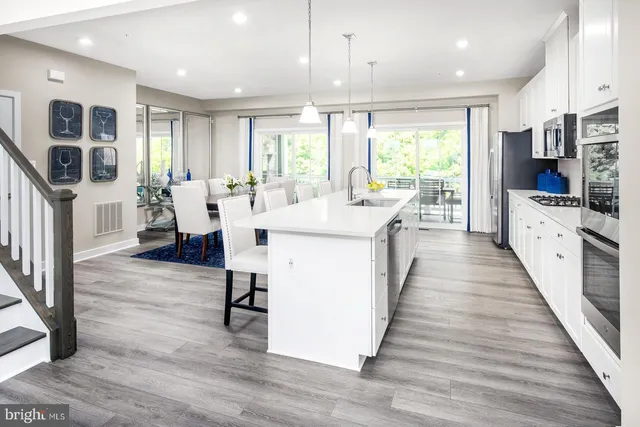 a large white kitchen with wooden floor and a large window