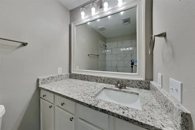 a bathroom with a granite countertop sink and a mirror