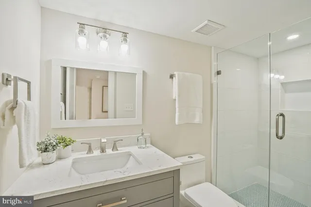 a bathroom with a granite countertop sink mirror vanity and toilet