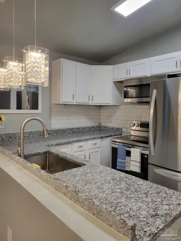 a kitchen with kitchen island granite countertop a sink cabinets and stainless steel appliances