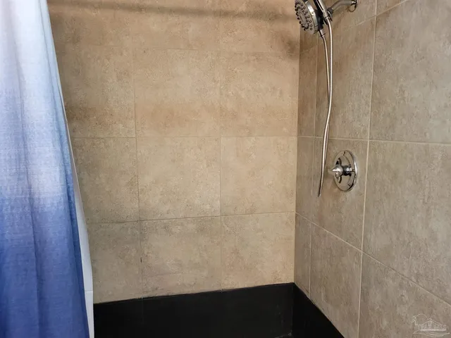 a view of an empty room with window and chandelier fan