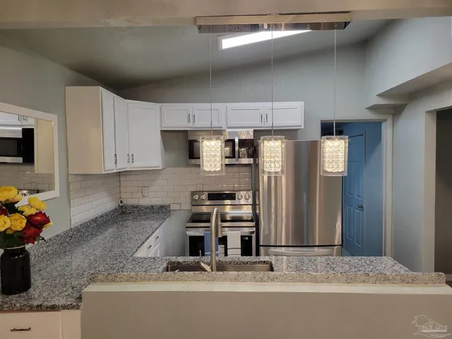 a kitchen with stainless steel appliances granite countertop a refrigerator a stove and a sink