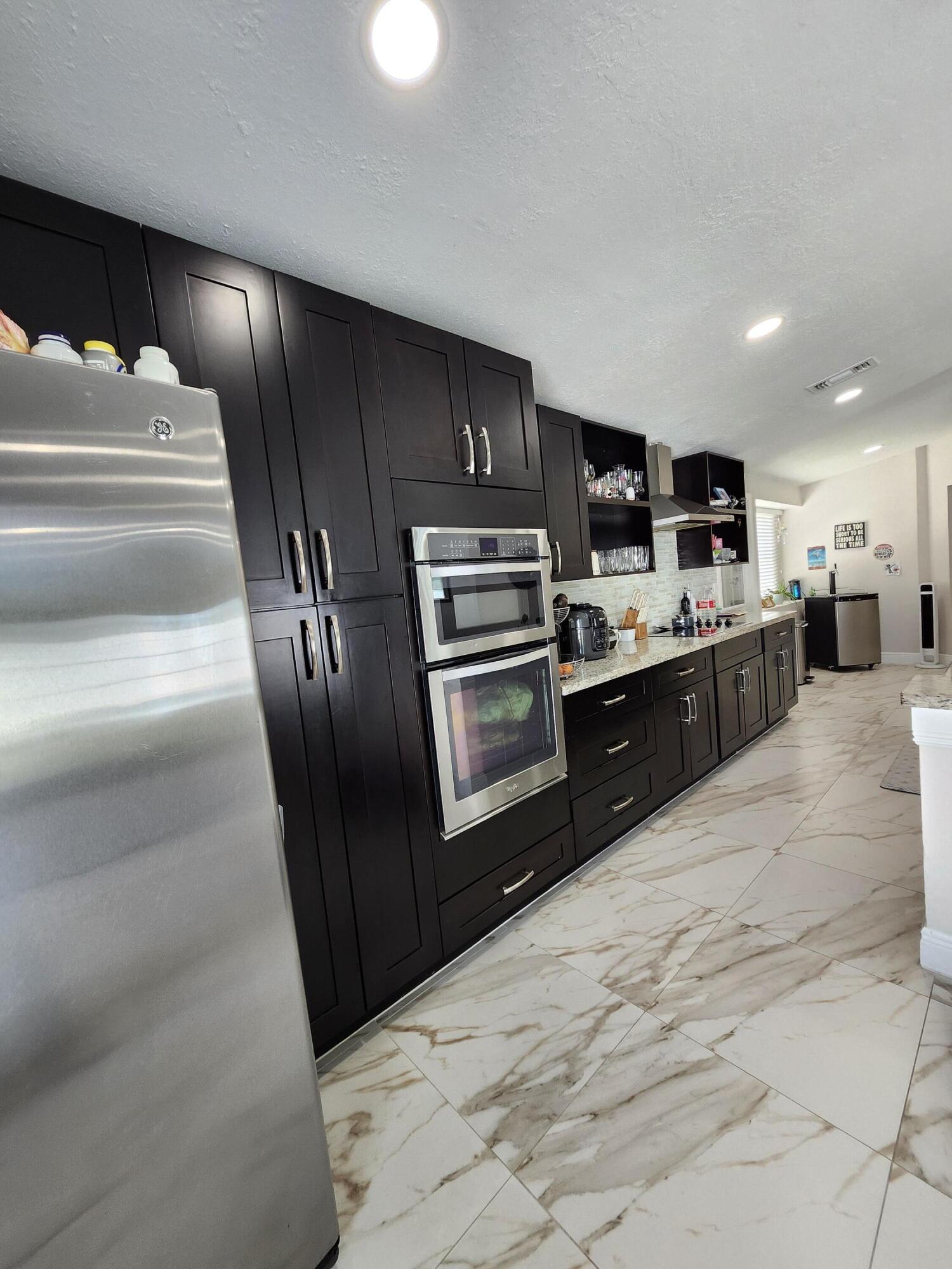 1473 Donwoods Lane Royal Palm Beach, FL 33411 - Photo 20 of 95 a kitchen with stainless steel appliances granite countertop a refrigerator and a stove top oven
