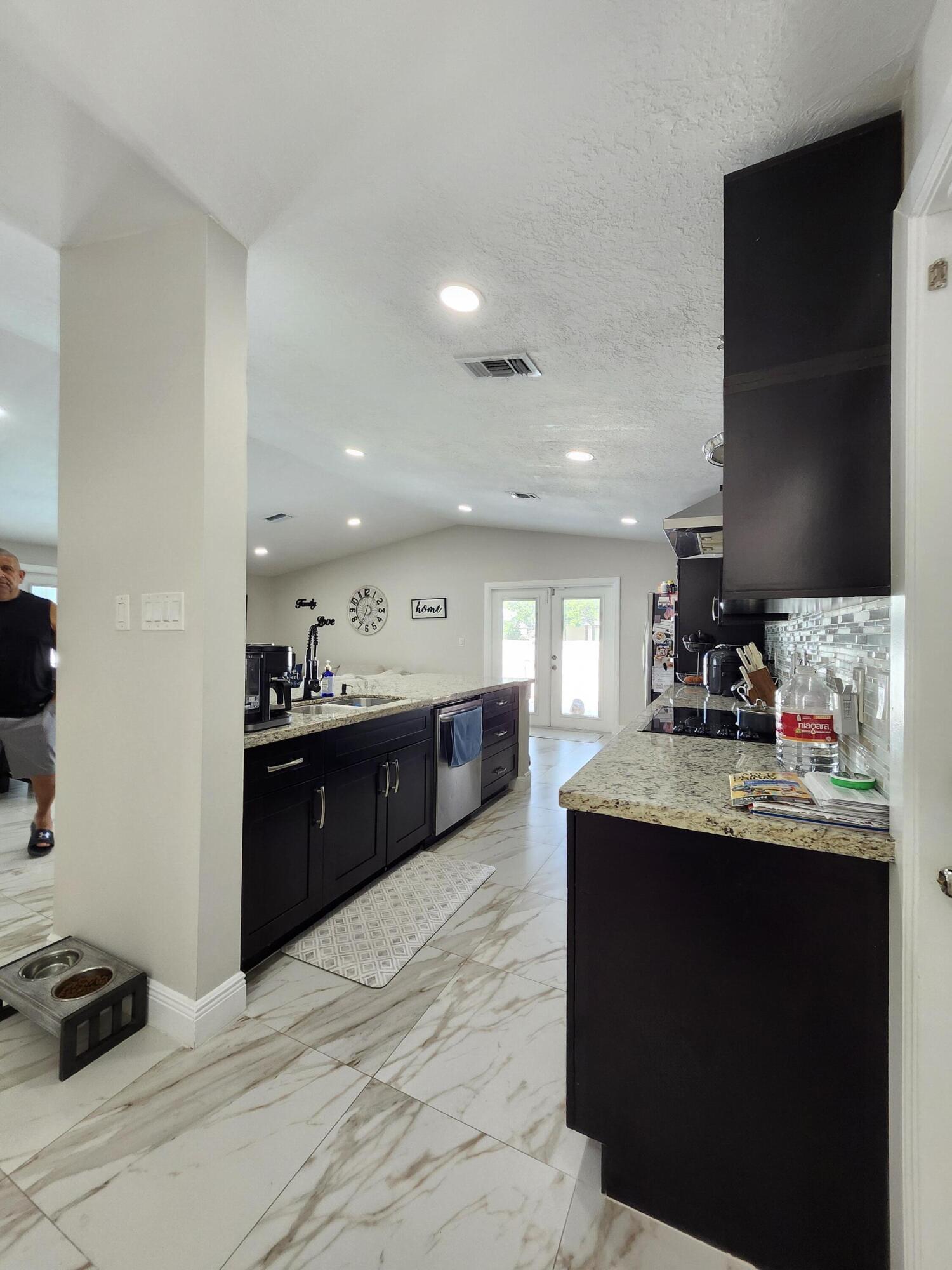 1473 Donwoods Lane Royal Palm Beach, FL 33411 - Photo 25 of 95 a kitchen with kitchen island granite countertop a sink stainless steel appliances and cabinets