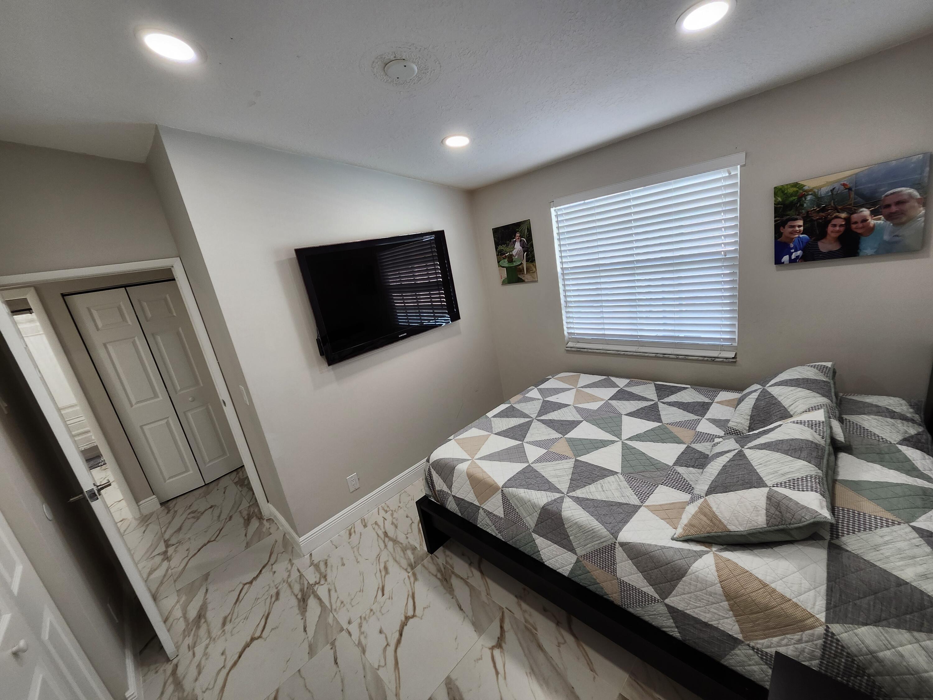 1473 Donwoods Lane Royal Palm Beach, FL 33411 - Photo 56 of 95 a bedroom with a bed and flat screen tv
