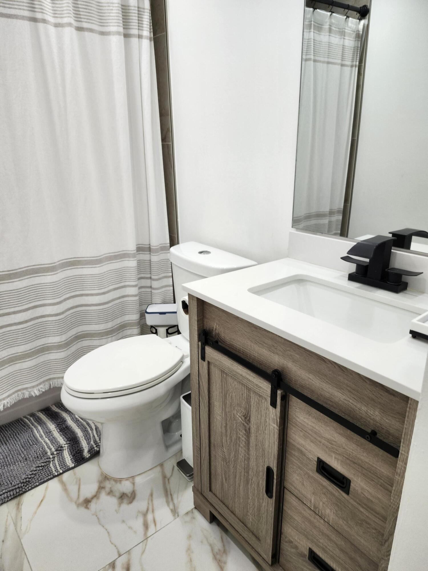 1473 Donwoods Lane Royal Palm Beach, FL 33411 - Photo 60 of 95 a bathroom with a sink a toilet and mirror
