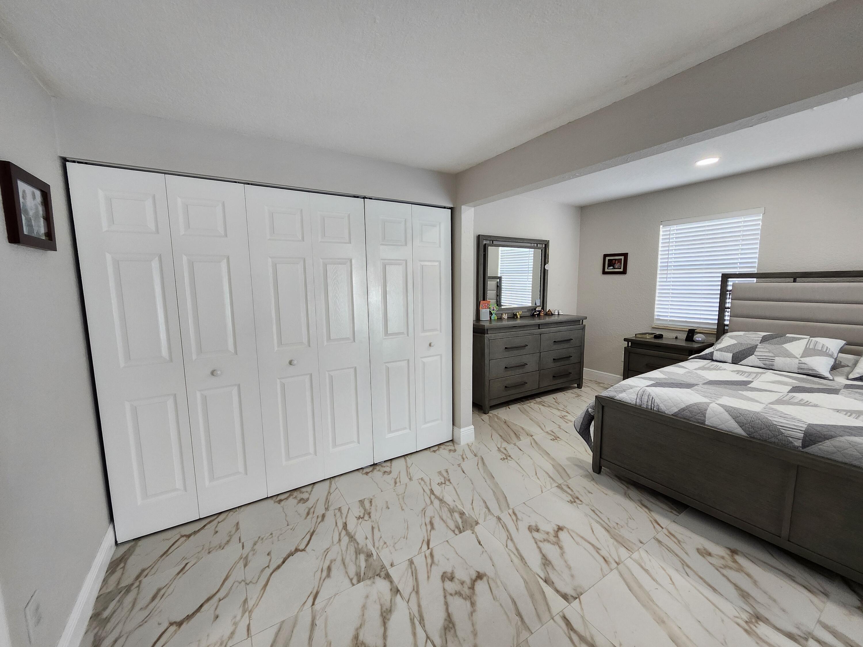 1473 Donwoods Lane Royal Palm Beach, FL 33411 - Photo 77 of 95 a bedroom with a bed and a large mirror