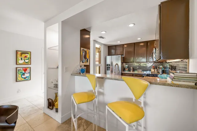 a living room with stainless steel appliances furniture a couch and a kitchen view