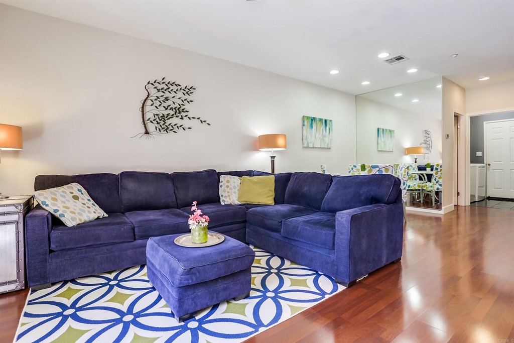 a living room with a couch and a dining table with wooden floor