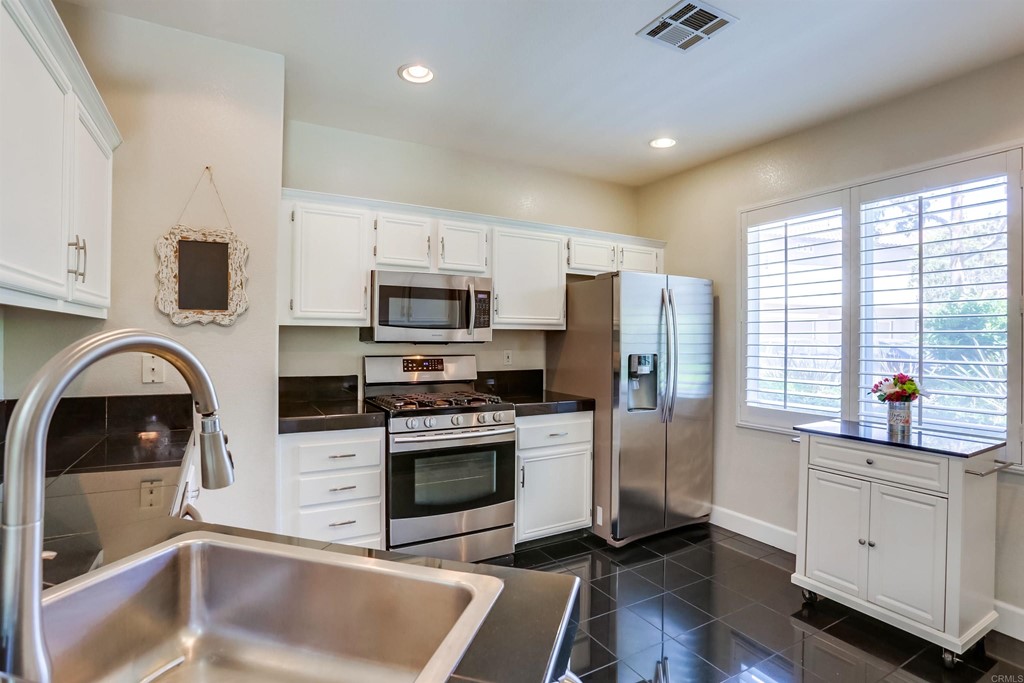 6094 Citracado Circle Carlsbad, CA 92009 - Photo 8 of 28 a kitchen with stainless steel appliances a stove a sink a refrigerator a window and cabinets