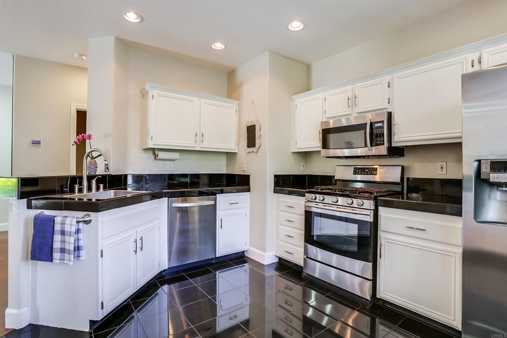 6094 Citracado Circle Carlsbad, CA 92009 - Photo 9 of 28 a kitchen with stainless steel appliances granite countertop a stove a sink and a microwave